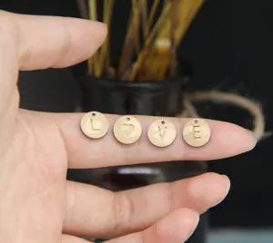 Detailaufnahme von runden DIY-Metallbuchstaben-Anhängern, graviert mit Buchstaben für Schmuck.