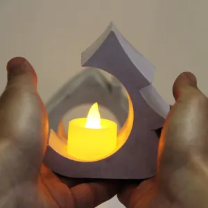 Close-up detail of a concrete house candle holder with warm LED tea light in hands.
