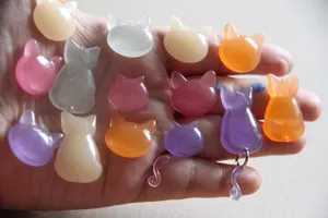 Close-up detail van doorzichtige hars kattenkop en staart bedels, kleurrijke schattige accessoires.