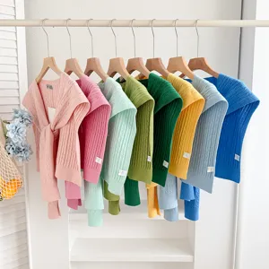 Close-up of colorful knit shawls hanging neatly on a rack, spring autumn fashion layering accessories.