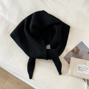 Detailed view of a black knitted triangular scarf, woolen blend fabric, cozy winter warm accessory.