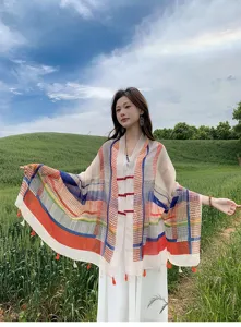 Outdoor detail shot of a colorful plaid cape shawl with Chinese buttons in a sunny field.