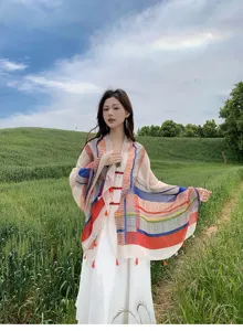 Outdoor scene showing a colorful geometric print tassel shawl and white dress detail in spring.