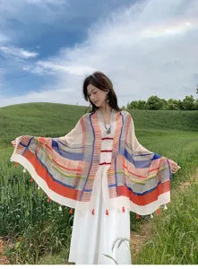 Detail shot of outdoor scenic background showing colorful block pattern shawl and frog button design.