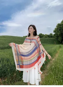 Colorful striped shawl detail showing traditional knot buttons and tassels in outdoor setting.