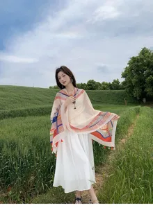 Detailed shot showing the colorful geometric patterned scarf and tassel edge worn outdoors.