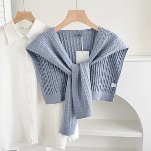 Knitted shawl detail view, stylish blue cape sweater accessory layered over white shirt.