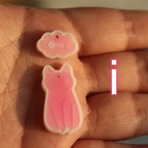 Primo piano di ciondoli in resina gatto e nuvola carini, accessori artigianali fai da te.