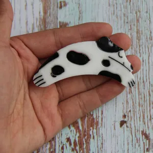 Cute black and white spotted dog hair clip detail view, stylish resin hair accessory.