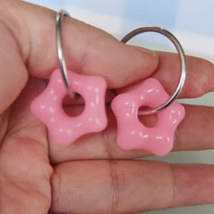 Detailed shot of cute pink star donut resin charms with silver hoop earrings for DIY jewelry.