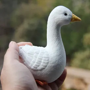 Hand-held white goose figurine detail shot, textured feather sculpture ornament display.