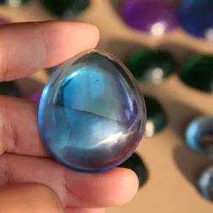 Close-up detail of a smooth teardrop resin gemstone in hand, showing crystal clear blue color.