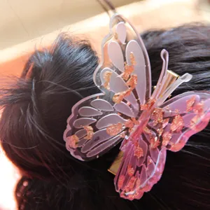 Detailed close-up of a stunning pink resin butterfly hair clip with shimmering gold foil accents.