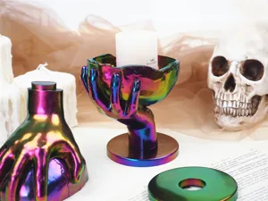 Regenbogenfarbener handfömiger Kerzenhalter mit gotischer Totenkopf-Dekoration.