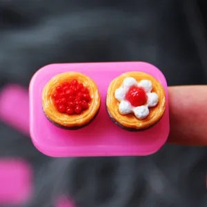 Nahaufnahme Detail von Miniatur Harz Kuchen Charms mit Beeren und Sahne Dekorationen.