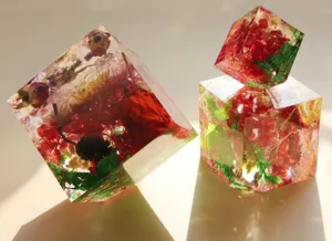Dettaglio ornamento cubo in resina con fiori secchi mostra consistenza e strati floreali.