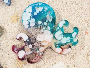 Handmade octopus resin craft with ocean theme, crystal epoxy art piece displayed on sand.