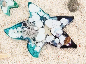 Resin starfish craft detail, ocean theme ornament with embedded stones and shells, beach style.