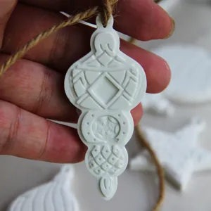 Nahaufnahme des weißen Weihnachtsschmuck-Anhängers mit feinen geprägten Schneeflocken-Mustern.