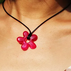 Close-up view of a pink resin flower pendant on a black cord necklace, smooth detail.