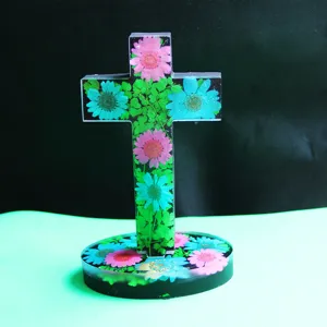 Gros plan de la croix en résine décorée avec des fleurs séchées colorées et un support rond.