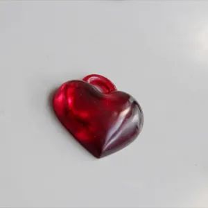Vista dettagliata ciondolo cuore 3D rosso, charm in resina liscia per creazione gioielli.