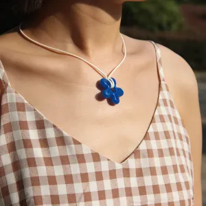 Blue flower pendant necklace with white cord rope chain, handmade resin floral jewelry detail view.