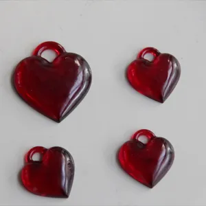 Vista ravvicinata di ciondoli lucidi in resina a forma di cuore rosso con dettagli lisci.