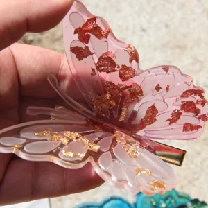 Close-up detail view of the pink butterfly resin hair clip with shiny gold foil flakes inside.
