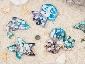 Detailed view of DIY ocean animal epoxy resin pieces featuring jellyfish and starfish on sand.