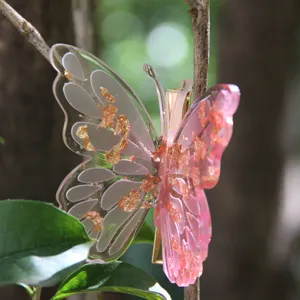 Detail view of a translucent pink resin butterfly hair clip with gold foil flakes on green leaves.