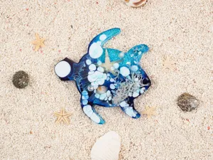Detailed close-up of a resin sea turtle ornament filled with ocean sand, shells and starfish.