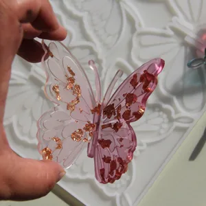 Handmade resin butterfly with gold foil flakes for DIY hairpins and home decor crafts.