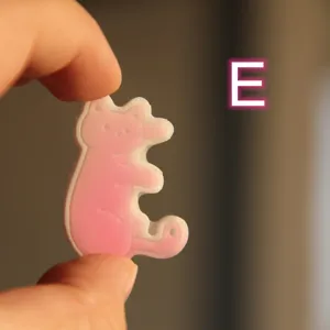 Vista dettagliata del ciondolo in resina lettera gatto, accessorio in silicone gatto rosa.