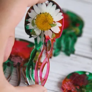 Handgefertigter Quallen-Harzanhänger Detail mit eingegossenem weißem Gänseblümchen und bunten Tentakeln.