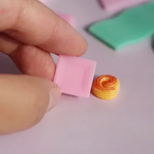 Detalle de molde de resina en miniatura con bandeja cuadrada rosa y pequeño dije de espiral.