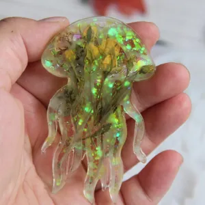 Handgefertigter Harz Quallen Anhänger mit Trockenblumen und Glitzer für DIY Schmuckherstellung.