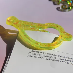 Resin bookmark detail shot showing translucent yellow glitter finish on book page.