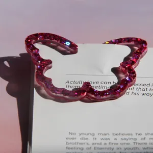 Close-up of a pink glitter butterfly bookmark or accessory detail, featuring shimmering resin effect.