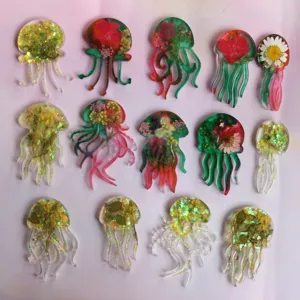 Detailansicht handgefertigter Epoxidharz-Quallen-Anhängerformen mit Trockenblumen und Glitzer.