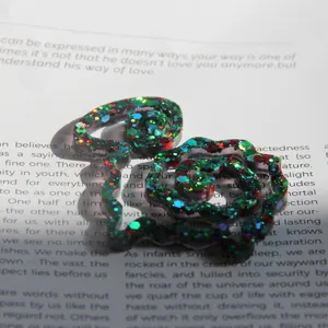 Close-up detail of glitter resin craft bookmark featuring colorful sparkles on paper background.