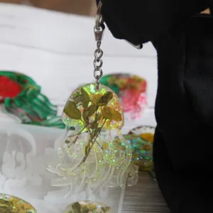 Handgefertigter Epoxidharz Quallen Schlüsselanhänger mit Trockenblumen und Glitzer Details.
