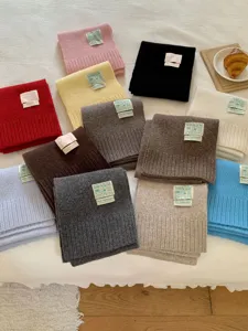 Vue détaillée d'écharpes en tricot douillet de diverses couleurs avec des étiquettes.