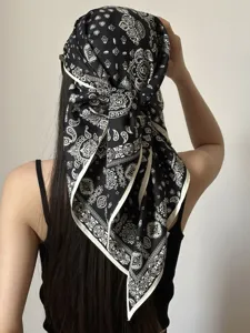 Detailansicht eines schwarz-weißen Paisleymuster Dreiecktuchs, getragen von einem Model.