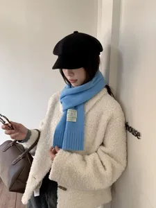Détail écharpe tricotée bleue, texture douce avec patch élégant, accessoire mode d'hiver chaud.