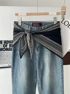 Detailansicht von blauen Jeans, dekoriert mit einem schwarzen Paisleymuster-Tuch.