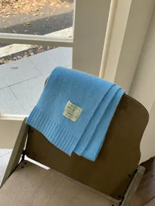 Détail écharpe en tricot bleu douillet, tissu doux avec écusson, tour de cou chaud hiver.