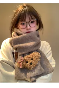 Cozy winter knit scarf detail featuring a cute fluffy teddy bear patch and red bow.