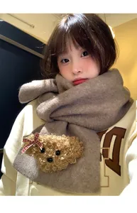 Close-up of a soft winter knitted scarf featuring a cute fluffy teddy bear with bow detail.
