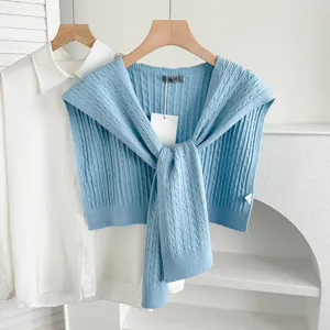 Blue cable knit shawl cape paired with white shirt, stylish layered sweater accessory for women.